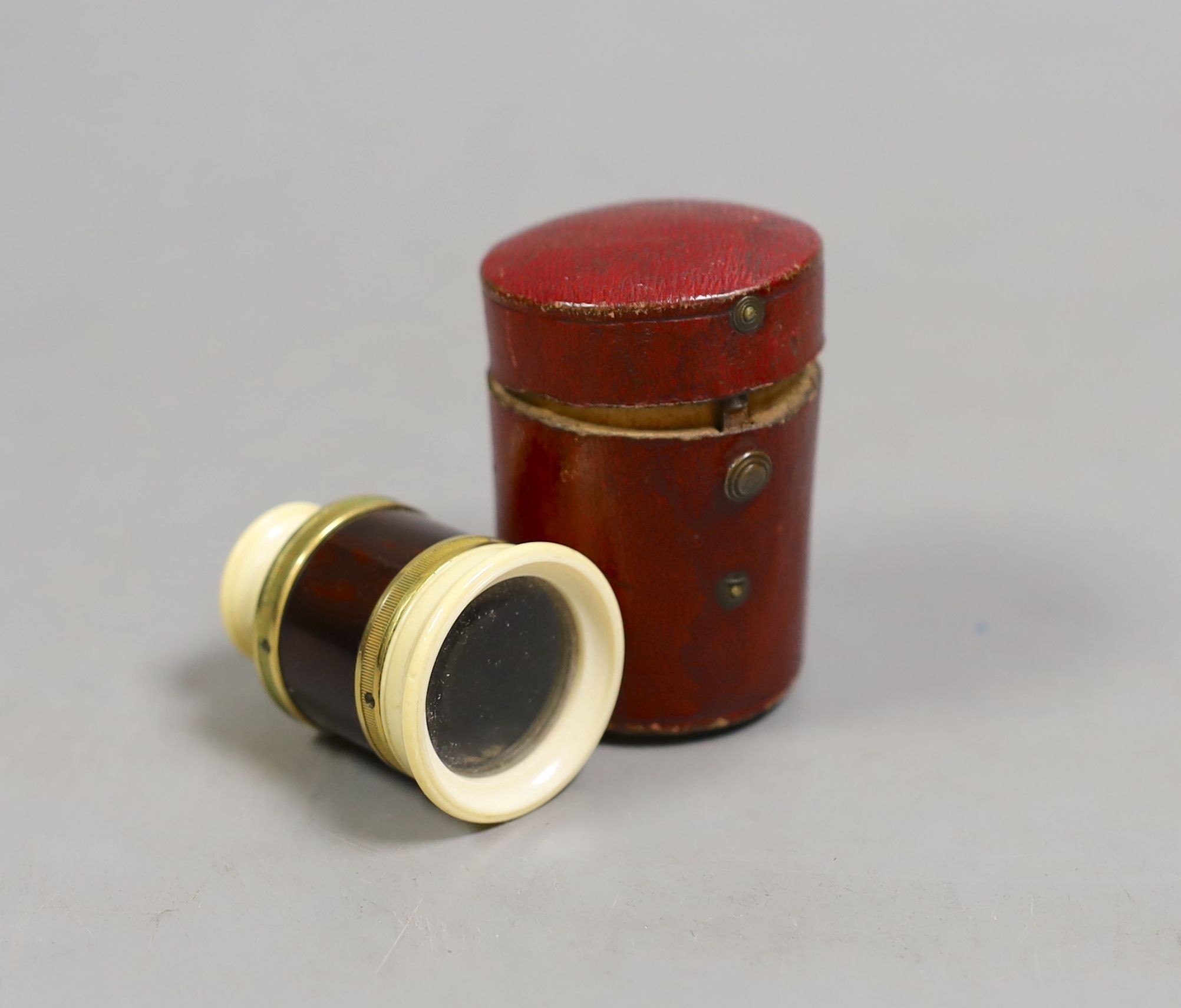 A 19th century ivory and tortoiseshell monocular in red leather case., Monocular 4.5 cms high, case 5.5 cms high.